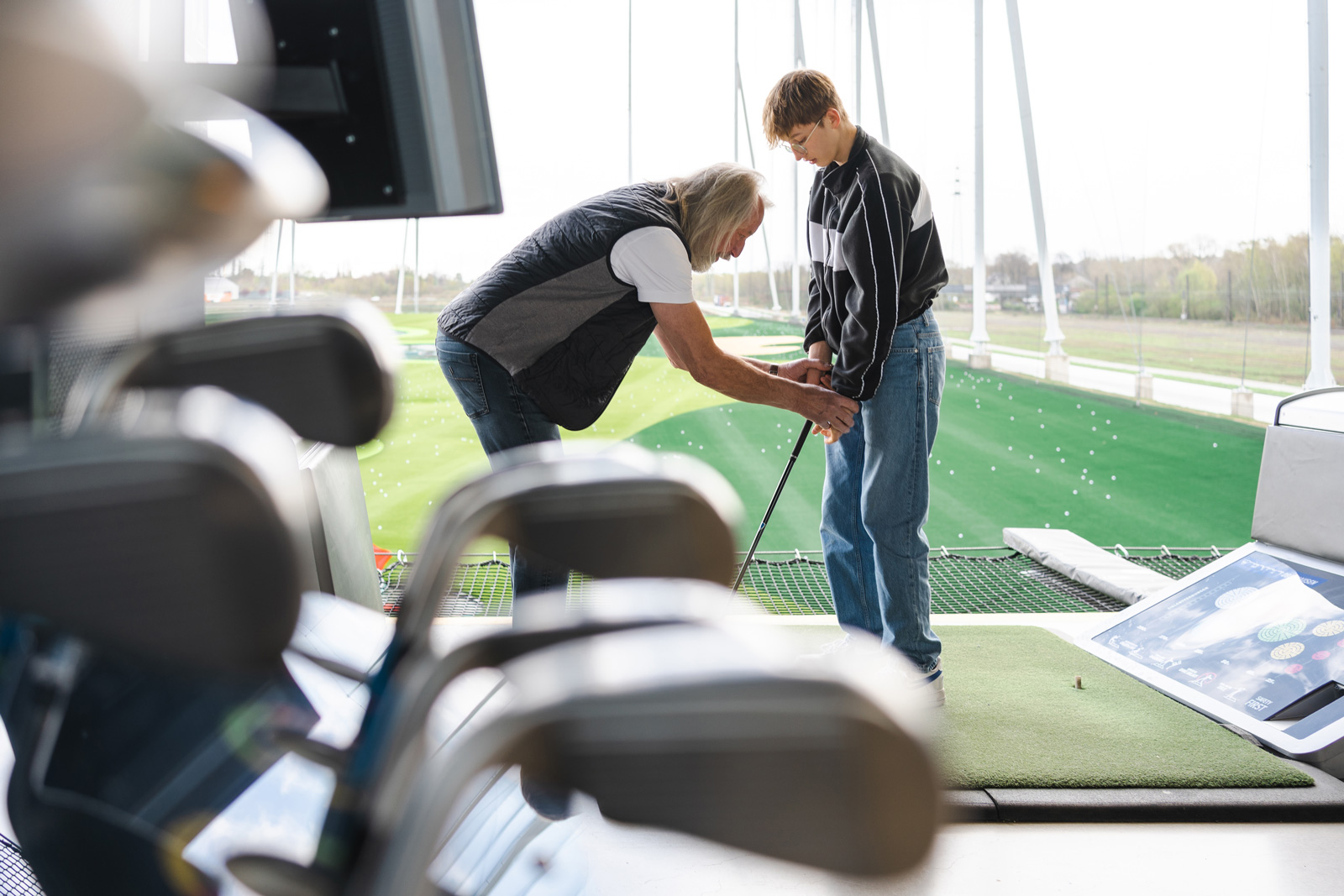 Young golfer receiving advice from a coach on best posture before swinging.