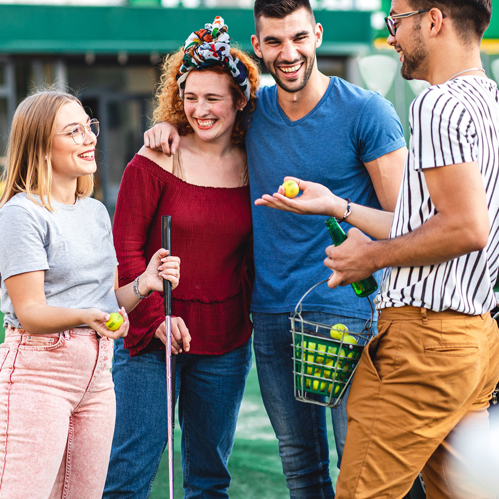 Four friends talk and smile, clubs and balls in hand.